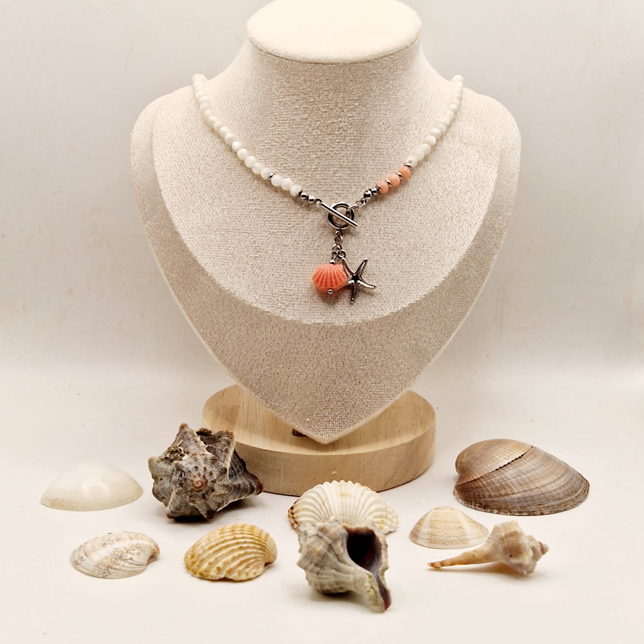 naszyjnik z masy perłowej ikorala z motywemmorskim,koloru krem i róz,stalszlachetna w kolorze srebrnym.demo na postumencie