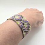 Bransoletka w stylu art-deco,wtszywana z koralikow szklanych,w gemetryczne wzory.Połączenie kolorów złota i pastelowych barw-